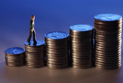 Image of business person walking up stacks of coins showing the need to create project budgets.