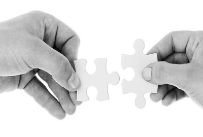 Image of two hands, each holding a puzzle piece signifying the need to employ project job descriptions.