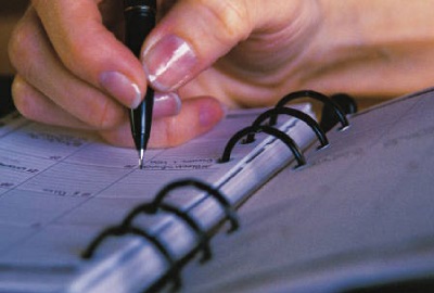 Image of business woman writing in her appointment book signifying the need for proper scheduling strategies.