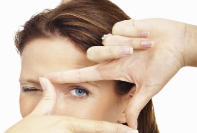 Image of woman with her hands forming a directors frame over her eye as if to perform a status quo analysis.