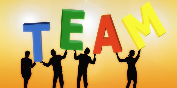 Image of four people holding up the letters 'TEAM', depicting the need to evaluate team performance.
