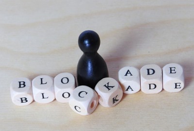Image of chess piece with building blocks spelling out 'blockade' depicting barriers to productivity.